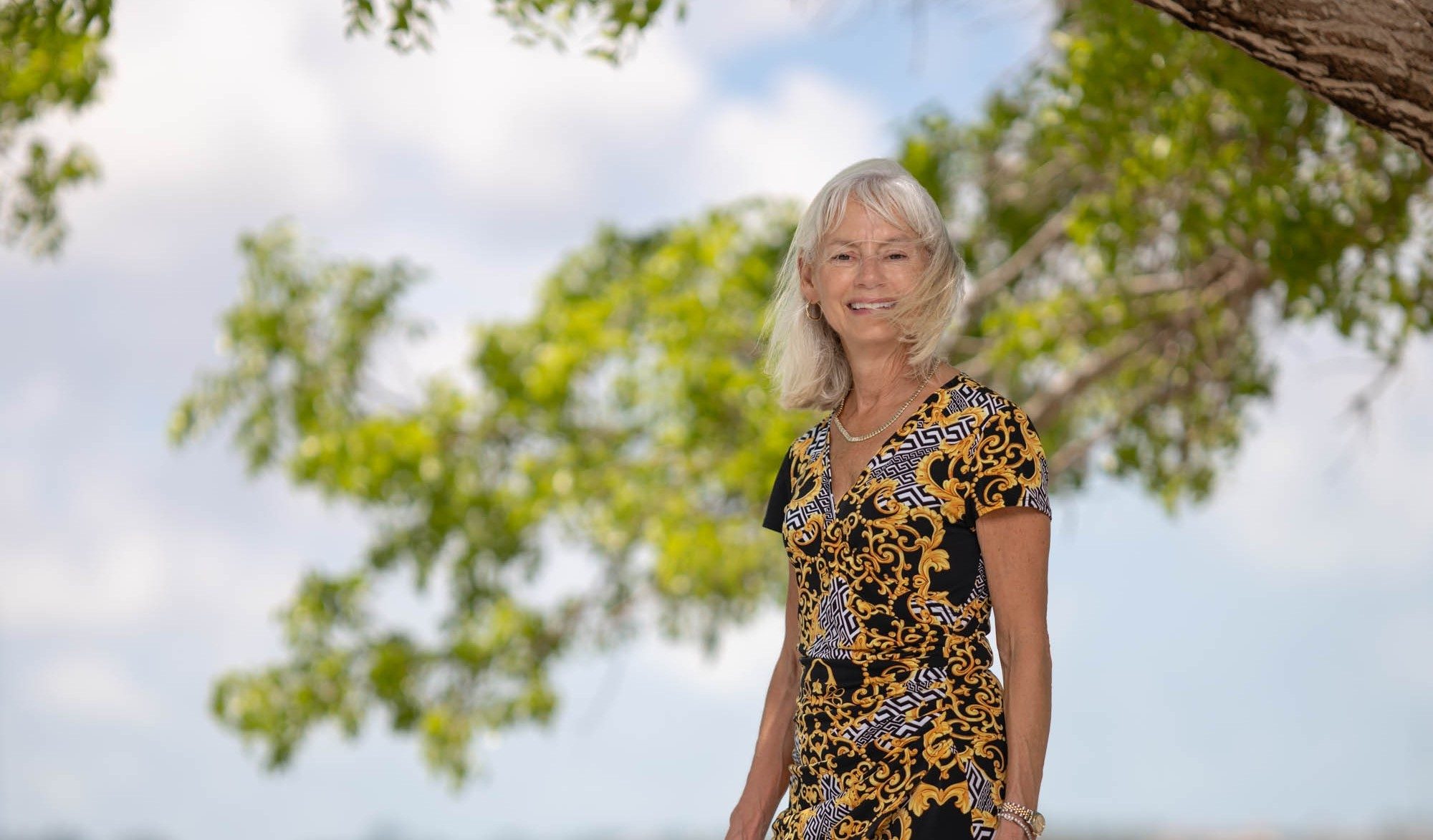 Beth Bradburn SRQ Magazine portrait smiling under a tree near the waterfront